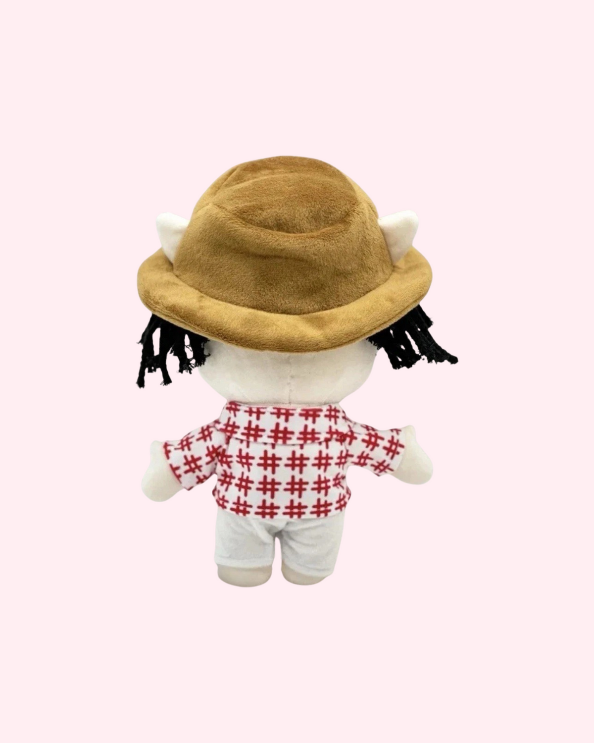 Back view of Bad Bunny Hello Kitty plush with a brown hat, a red-and-white patterned shirt and white shorts, on a pale pink background.