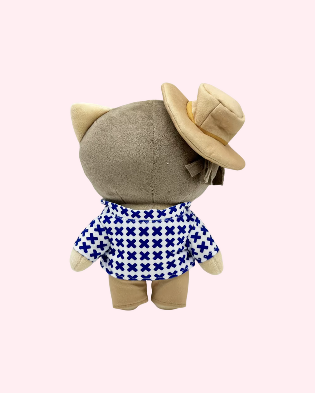 Back view of Bad Bunny Hello Kitty plush showing a cream hat and blue-and-white patterned shirt on a pale pink background.