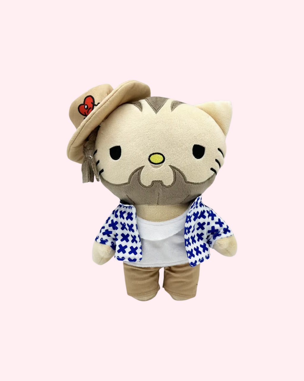 Front view of Bad Bunny Hello Kitty plush with a cream hat, patterned blue-and-white shirt and beige trousers on a pale pink background.