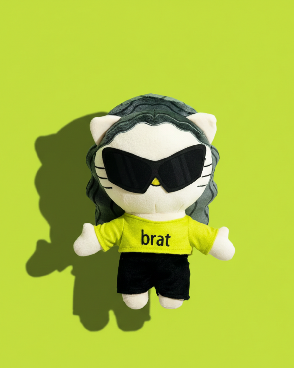 Charli xcx Hello Kitty plush against a bright lime green wall in sunlight.