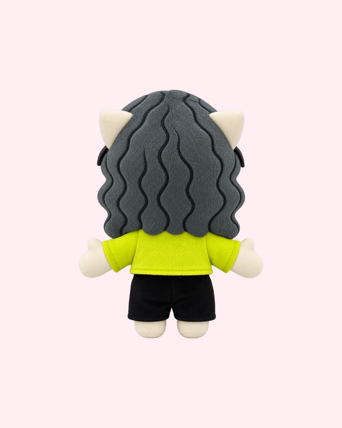 Back view of Charli xcx Hello Kitty plush with long dark wavy hair, a lime green shirt and black shorts, on a pale pink background.