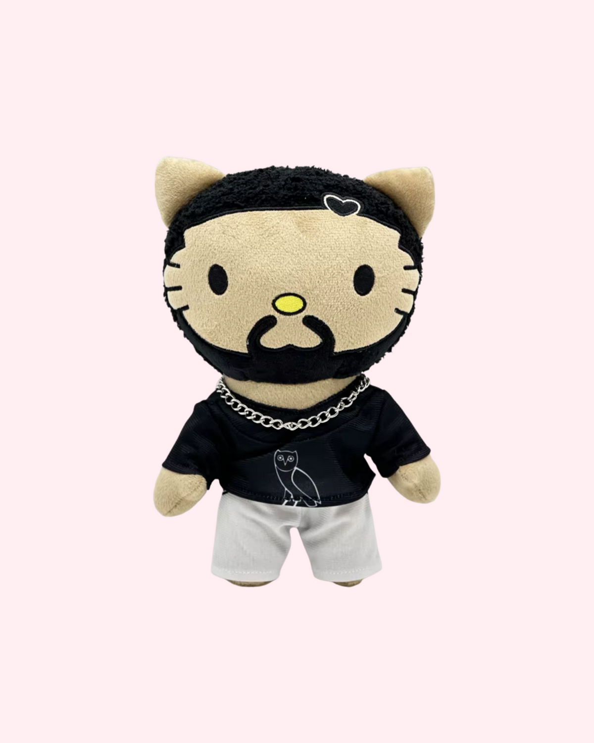 Front view of Drake Hello Kitty plush with a black owl T-shirt, silver chain and white shorts, on a pale pink background.