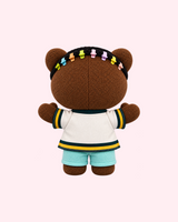 Back view of Drake Hello Kitty plush showing a cream jersey with green-and-yellow trim and pale blue shorts on a pale pink background.