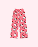 Front view of coral pink Hello Kitty pajama pants with white character faces and red bows
