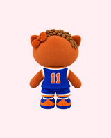 Back view of Jalen Brunson Hello Kitty plush showing a blue number 11 jersey and orange-and-blue sneakers on a pale pink background.