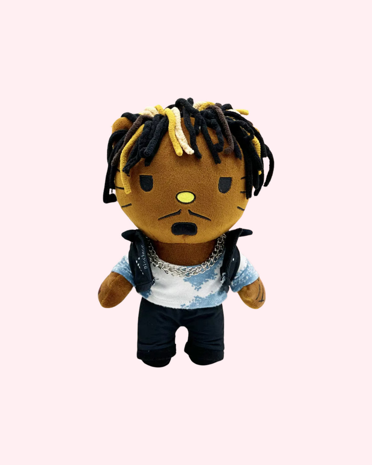 Front view of Juice WRLD Hello Kitty plush with black-and-blond yarn dreadlocks, a silver chain, a blue-and-white tie-dye shirt and a black vest, on a pale pink background.