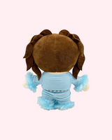 Back view of Kali Uchis Hello Kitty plush showing brown hair and a light blue outfit on a pale pink background.