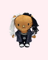 Front view of Ken Carson Hello Kitty plush with black-and-white yarn hair, dark clothes and silver-tone chains on a pale pink background.