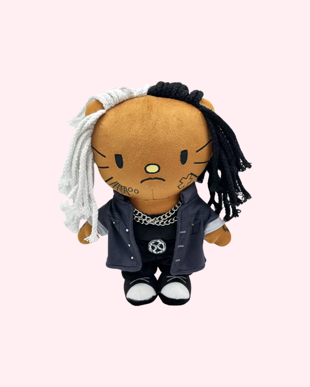 Front view of Ken Carson Hello Kitty plush with black-and-white yarn hair, dark clothes and silver-tone chains on a pale pink background.