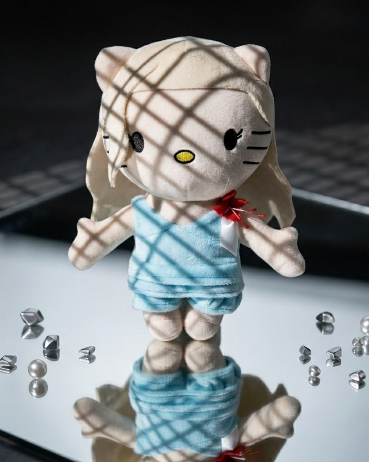 Lady Gaga Hello Kitty plush on a mirrored surface with scattered clear crystals and patterned light.
