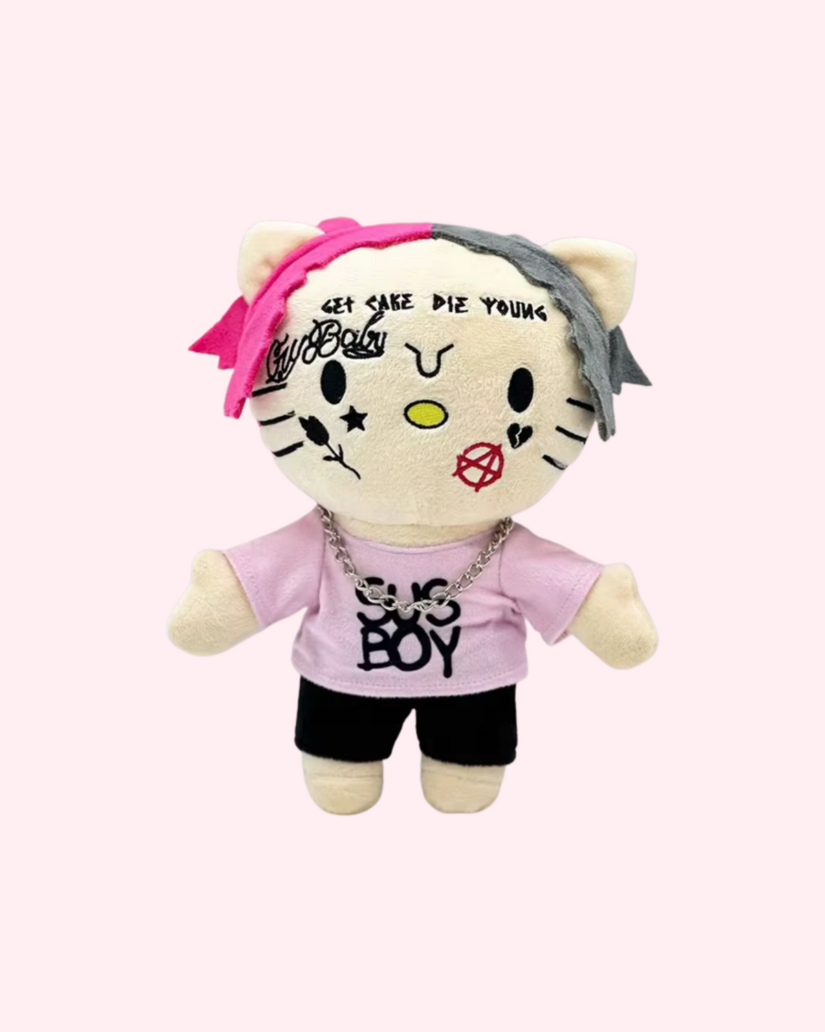 Front view of Lil Peep Hello Kitty plush with pink-and-black hair, embroidered face tattoos, a pink shirt and black shorts, on a pale pink background.