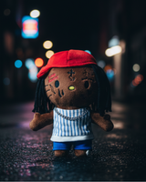 Lil Wayne Hello Kitty plush standing on a wet city street at night.