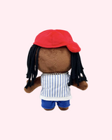 Back view of Lil Wayne Hello Kitty plush showing a red cap, black yarn hair and striped top on a pale pink background.