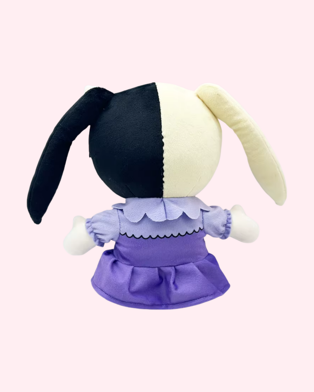 Back view of Melanie Martinez Hello Kitty plush with cream-and-dark pigtails and a purple dress, on a pale pink background.
