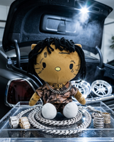 NBA YoungBoy Hello Kitty plush in an open car boot with silver-tone chains and jewellery.