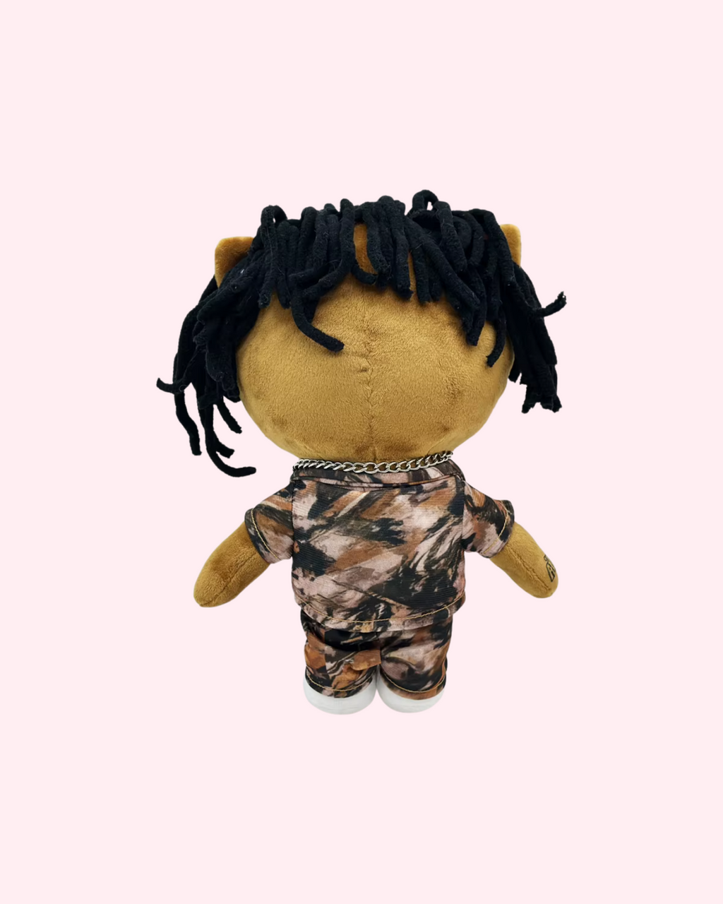 Back view of NBA YoungBoy Hello Kitty plush showing black yarn hair and a camouflage outfit on a pale pink background.