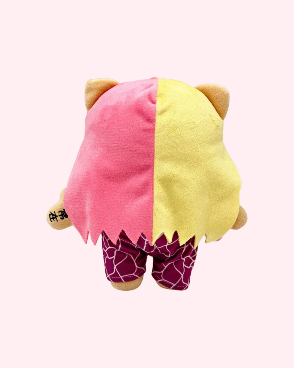 Back view of Nicki Minaj Hello Kitty plush showing long pink-and-blonde hair and magenta trousers on a pale pink background.