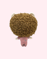 Back view of Post Malone Hello Kitty plush showing curly brown hair and a pink outfit on a pale pink background.