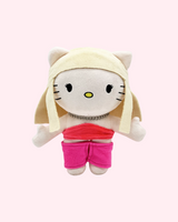 Front view of Taylor Swift Hello Kitty plush with blonde hair, a red top and pink shorts on a pale pink background.