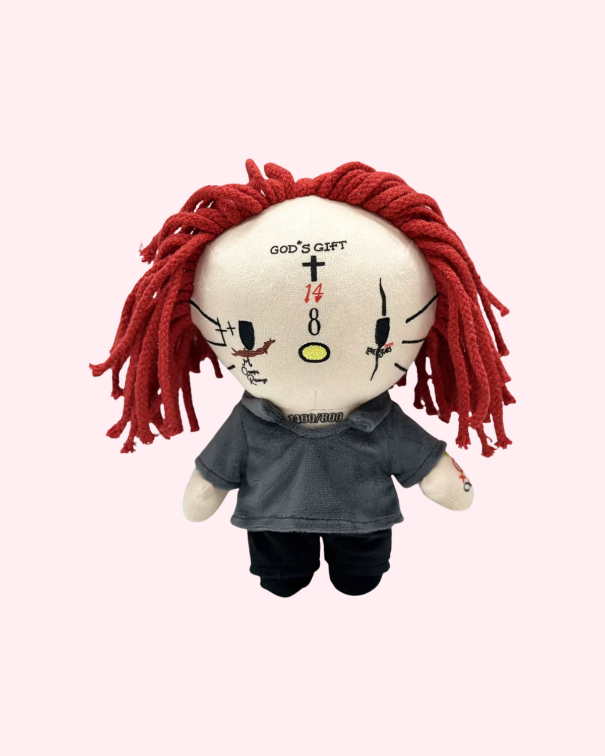 Front view of Trippie Redd Hello Kitty plush with red yarn hair and a dark outfit on a pale pink background.